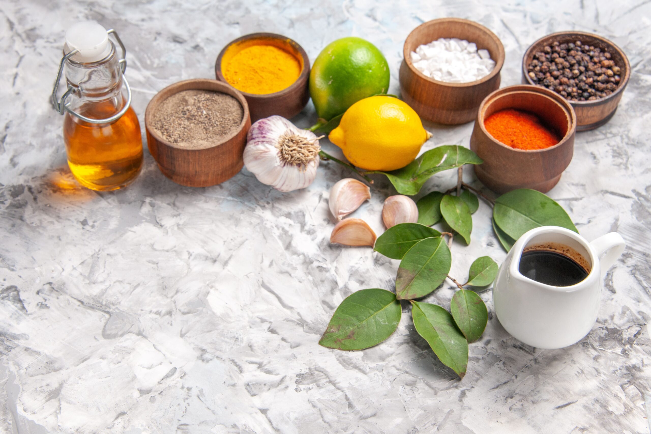 front-view-different-seasonings-with-lemon-garlic-white-floor-oil-spicy-fruit-salt